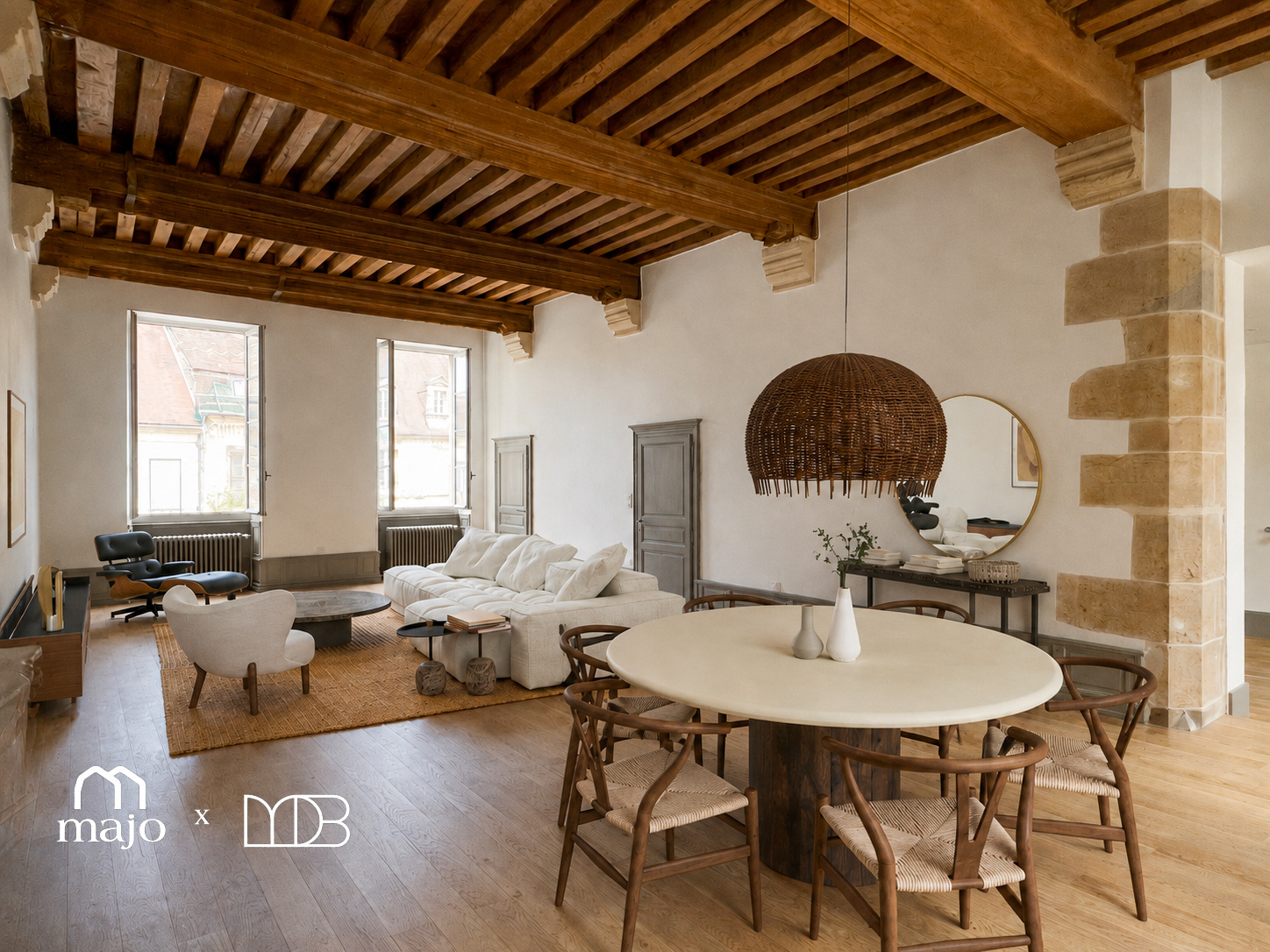 Grand séjour aux poutres apparentes et murs de pierre, table de repas et fauteuils